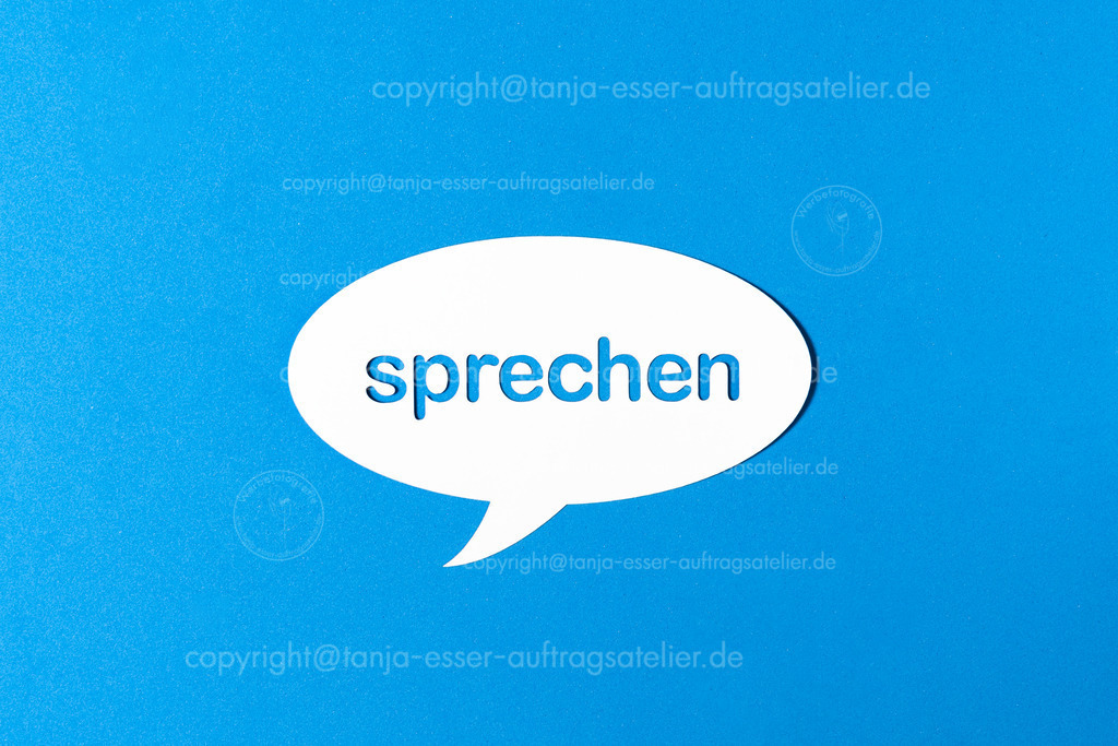 sprechen D | Deutsches Wort sprechen in einer Sprechblase aus Papier ausgestanzt vor blauem Hintergrund.