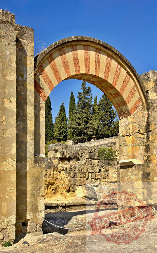 Medina Azahara horseshoe arch ruins in Córdoba, Spain. Spain - Cordoba | Ancient Moorish horseshoe arch framing cypress trees at the Medina Azahara archaeological site - Realized with Pictrs.com