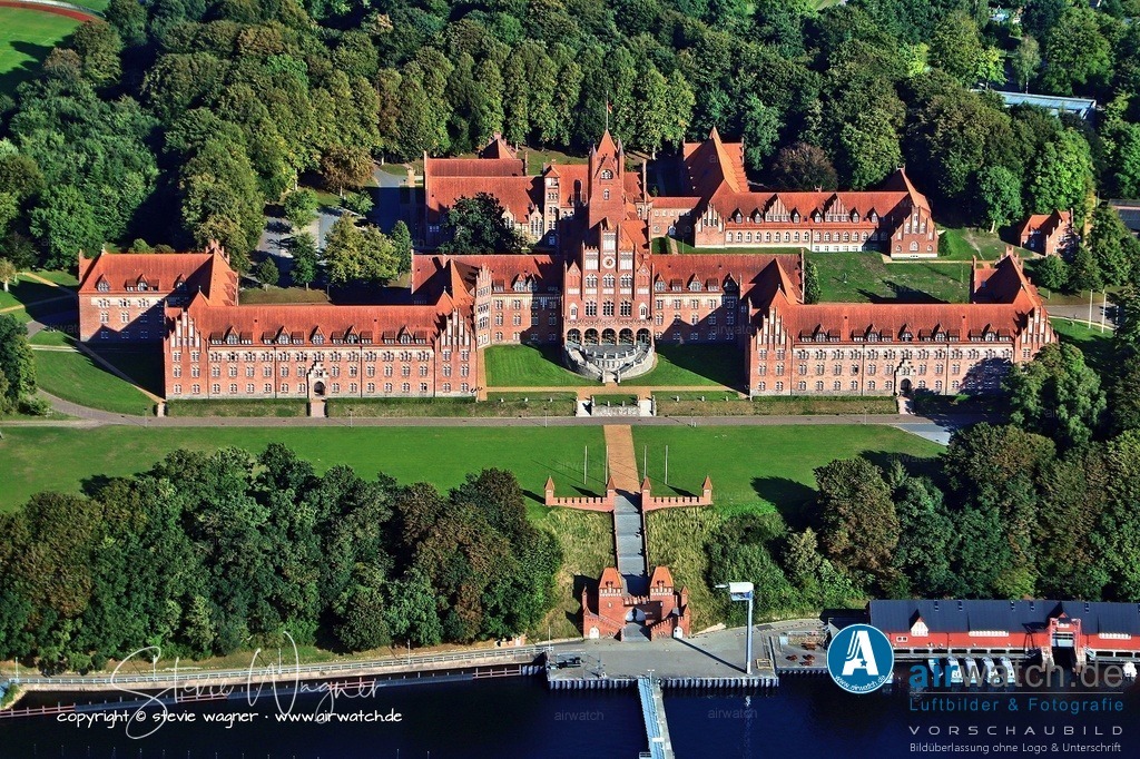 Luftbild Anflug Marineschule Muerwik - Die Schule wird auch als „Rotes Schloss am Meer“ bezeichnet. | Am 5. Juli 1956 wurde die Marine-Akademie in Kiel-Holtenau in Marineschule Mürwik umbenannt und die Ausbildung wieder aufgenommen. Seit der Wiedervereinigung 1990 bildet die Schule Offiziersanwärter aus ganz Deutschland aus. Die Schule wird auch als „Rotes Schloss am Meer“ bezeichnet und ist ein bedeutendes Kulturdenkmal.