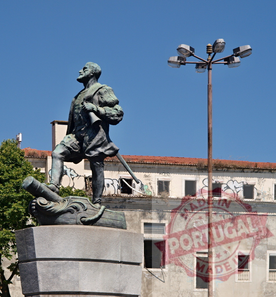 Bronze explorer statue facing urban decay and lamppost | Bronze explorer statue standing with cannon against building featuring graffiti and modern lamppost - Realized with Pictrs.com