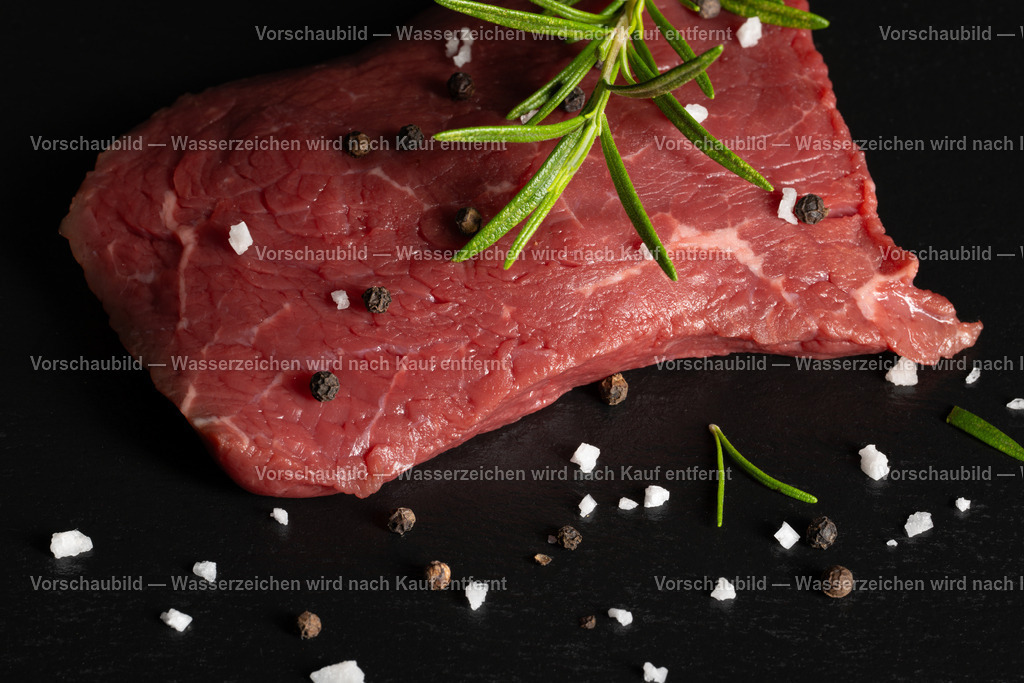 rohes Rinder Hüftsteak auf schwarzer Schieferplatte angerichtet | rohes Rinder Hüftsteak auf schwarzer Schieferplatte angerichtet. Dekoriert mt einen Zweig Rosmarien, Pfefferkörnern und groben Salz - Realisiert mit Pictrs.com
