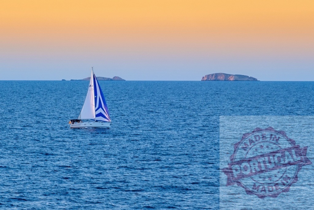 Sailboat cruising blue ocean towards islands at sunset | Sailboat cruising calm blue sea against an orange sky with distant islands - Realisiert mit Pictrs.com