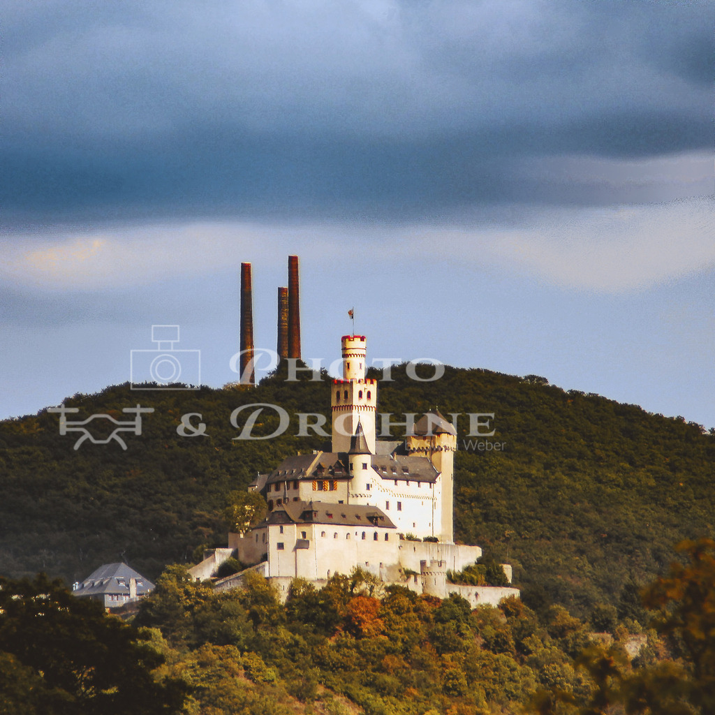 Marksburg-1920-2 | Die MArksburg und die drei typischen Schornsteine der historischen Bleihütte im Hintergrund. Heute beherbergt die Bleihütte eine der größten und modernsten Batterie-Recycling-Betriebe in Deutschland. - Realisiert mit Pictrs.com