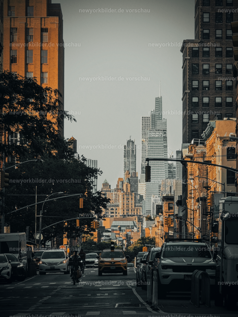 Streetlife in New York – Energie, Bewegung und urbane Kulisse | New York ist eine Stadt, die niemals stillsteht – und genau das spiegelt dieses Bild wider. Die Straße zieht den Blick in die Tiefe, flankiert von Radfahrern, Autos und Menschen, die ihrem Alltag nachgehen. Im Hintergrund erhebt sich das imposante One Vanderbilt, ein Symbol für die moderne Skyline Manhattans. Die Szene ist voller Bewegung und Energie: Gespräche auf den Gehwegen, das rhythmische Rollen der Fahrräder, das leise Brummen der Motoren. Hier verschmelzen Architektur und Leben zu einem pulsierenden Mosaik, das die Essenz der Metropole einfängt. Die Farben und Perspektive lassen den Betrachter die Dynamik spüren, als stünde er selbst mitten im Geschehen. Dieses Bild ist mehr als eine Straßenszene – es ist ein Gefühl, ein Moment, der die Kraft und Vielfalt New Yorks sichtbar macht. Wer die Stadt liebt, erkennt hier ihre Seele: urban, lebendig, inspirierend. Ein perfektes Motiv für alle, die die Energie der Großstadt in ihrer reinsten Form erleben möchten.