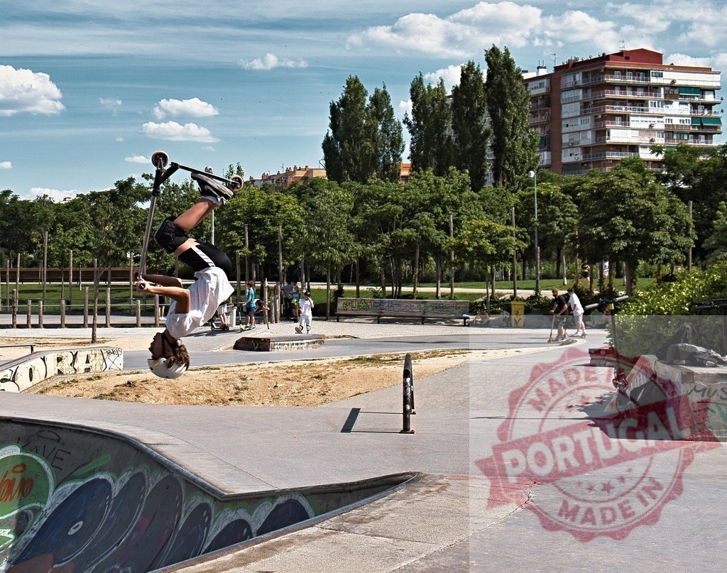 Young man performing backflip stunt on scooter at skatepark | Young man doing a backflip stunt on a kick scooter in an urban skatepark environment - Realisiert mit Pictrs.com