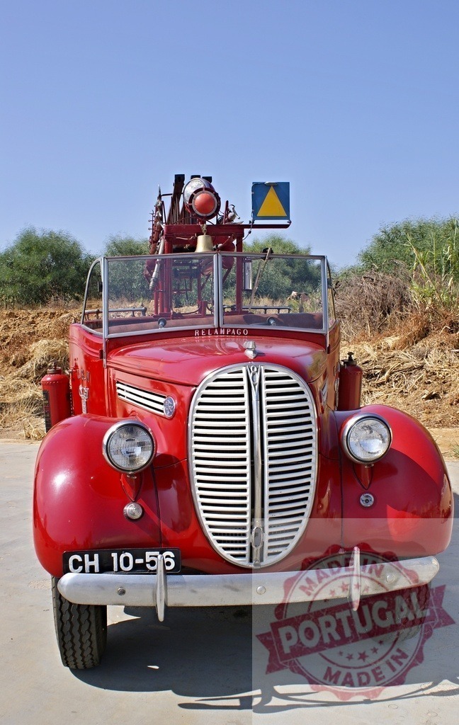 Vintage red firefighting truck with antique equipment | Vintage red firefighting truck parked outdoors under a clear blue sky - Realized with Pictrs.com