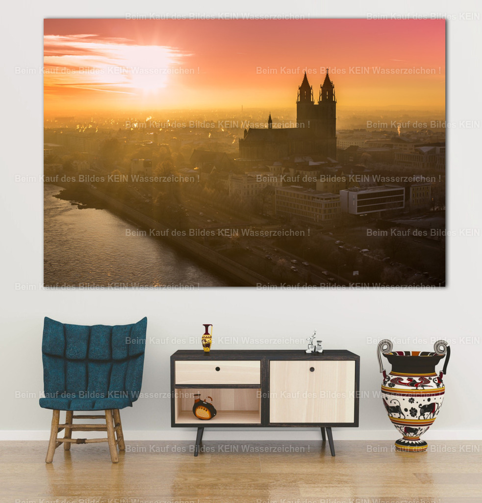 Luftbild Magdeburg Dom Sonnenuntergang Winter-0509 wall_office | Ein Meer aus warmem Gold und Orange umgibt die Silhouette des Magdeburger Doms. Die tief stehende Sonne taucht die Dächer der Altstadt in ein sanftes Licht, während die Elbe ruhig durch die Stadt fließt. Die markanten Doppeltürme des Doms heben sich eindrucksvoll vom leuchtenden Himmel ab und verleihen dem Motiv eine besondere Tiefe und Ruhe.Als großformatige Leinwand über einer Couch entfaltet dieses Luftbild seine warme, stimmungsvolle Wirkung. Die goldenen Farbtöne passen besonders gut zu natürlichen Materialien und schaffen eine angenehme Atmosphäre im Wohnzimmer oder in einem gemütlichen Rückzugsbereich. Auch auf Acrylglas kommt das intensive Farbenspiel eindrucksvoll zur Geltung.Das Motiv stammt aus meinem eigenen Luftbildarchiv und bringt ein Stück Magdeburg in die eigenen vier Wände – für alle, die sich der Elbestadt verbunden fühlen und außergewöhnliche Wandbilder schätzen. - Realisiert mit Pictrs.com