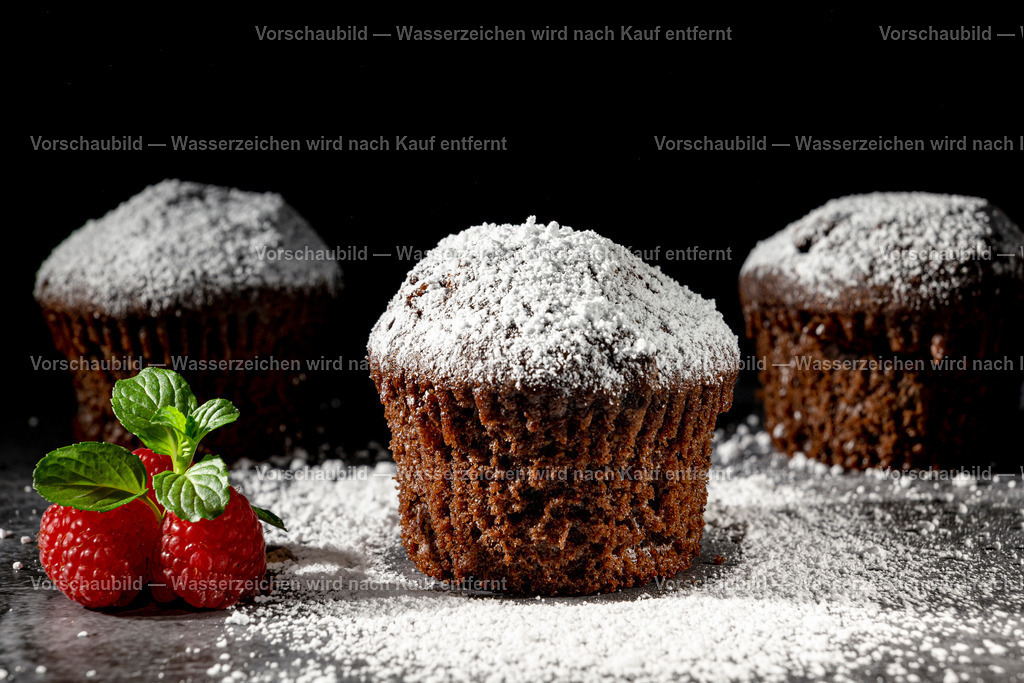 Schokomuffins mit Puderzucker bestreut | Schokomuffins mit Puderzucker bestreut., Dekoriert mit Himbeeren und Minzblatt. Low Key Aufnahme - Realisiert mit Pictrs.com