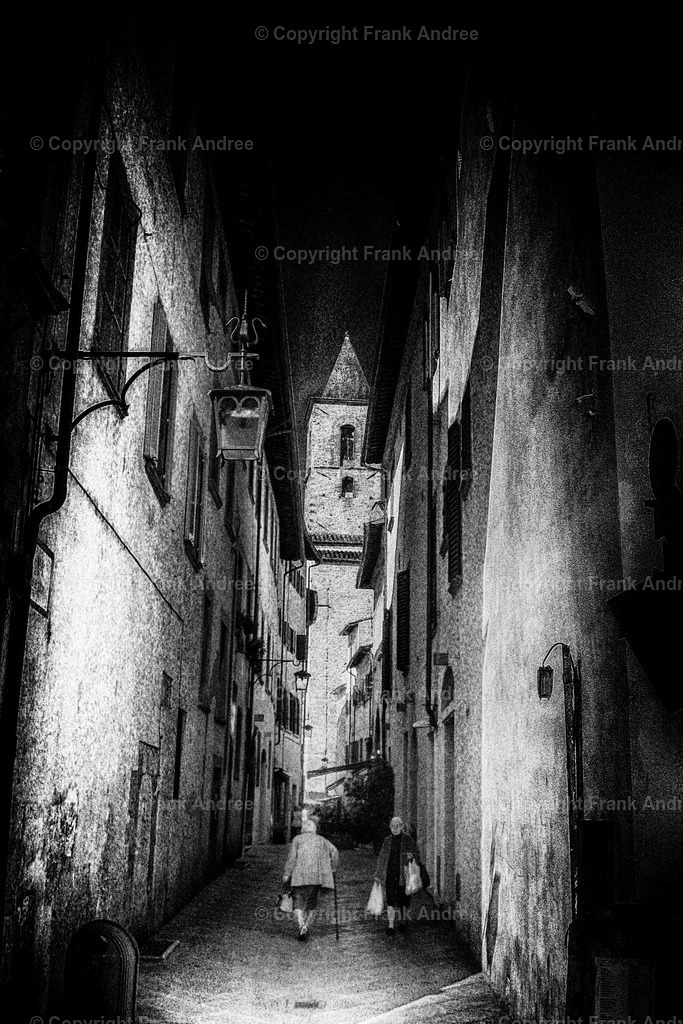 Flüchtige Begegnung | Zwei ältere Frauen begegnen sich in einer engen Gasse in der Toskana. Straßenfotografie aus Italien in schwarz und weiß. - Realisiert mit Pictrs.com