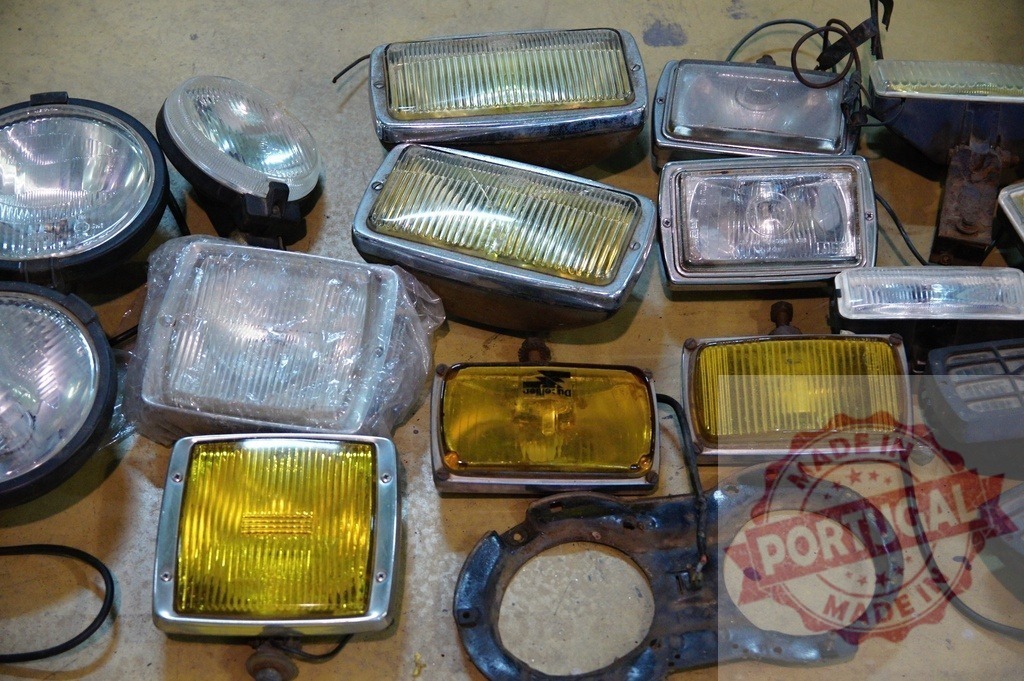 Collection of vintage car headlights and fog lights lying on a garage floor | Various old yellow and white car headlights and fog lights are scattered on a garage floor, creating a nostalgic automotive scene - Realisiert mit Pictrs.com