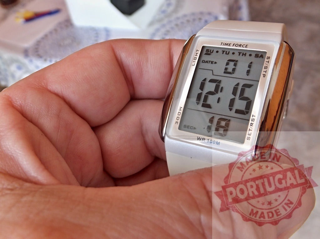 Hand holding a Time Force digital watch | Hand holding a white Time Force digital wristwatch displaying the time and date - Realisiert mit Pictrs.com