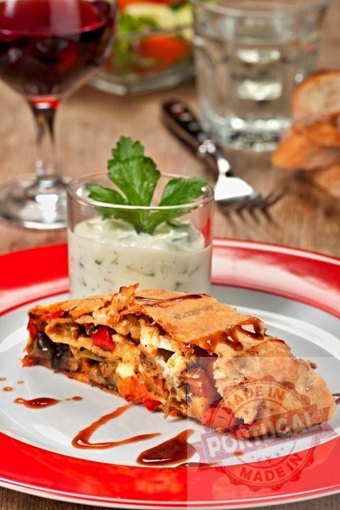 Vegetable strudel slice with balsamic glaze and dip | Savory vegetable strudel served with a creamy dip, red wine, and salad - Realisiert mit Pictrs.com