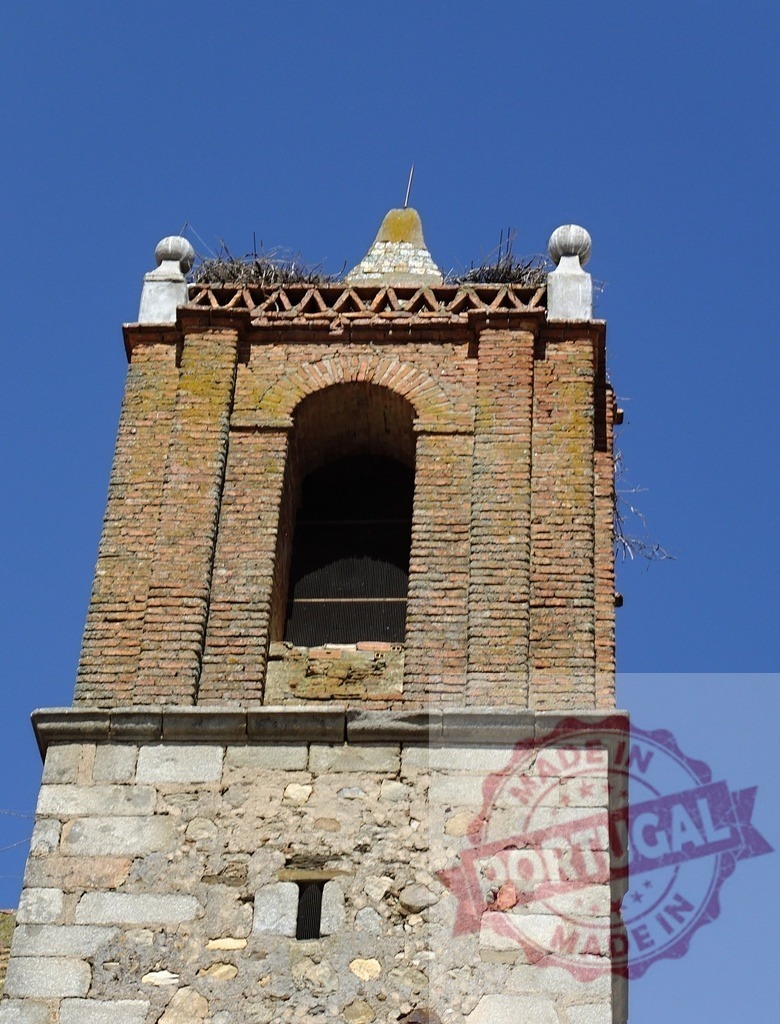 Church bell tower with stork nest under blue sky. Spain - Extremadura | Old brick and stone church bell tower with a stork nest on top against clear blue sky - Realisiert mit Pictrs.com
