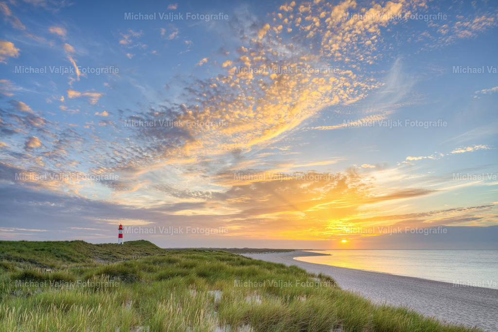 Sonnenuntergang auf Sylt | Wunderschöner Sonnenuntergang an einem Sommerabend am Ellenbogen auf der Nordseeinsel Sylt. Eine leichte Brise weht um das Gesicht, die Sonne schaut nochmal kurz durch einen Spalt in den Wolken und färbt die Wolken darüber bunt. Links ist der Leuchtturm List-Ost zu sehen, auf der rechten Seite die Nordsee.  - Realisiert mit Pictrs.com