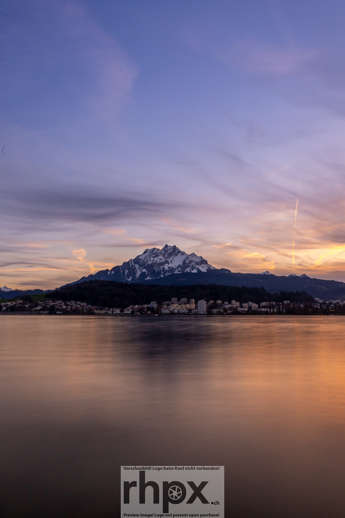 Sonnenuntergang mit Pilatus | Der Pilatus im goldenen Licht des Sonnenuntergangs – der Himmel färbt sich in sanften Pastelltönen, während sich die Stadt Luzern im stillen Wasser des Vierwaldstättersees spiegelt. Ein stimmungsvoller Moment zwischen Tag und Nacht. - Realisiert mit Pictrs.com