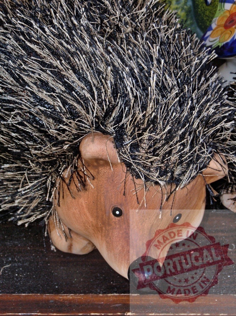 Ceramic hedgehog figurine with spiky texture decorating shelf | Ceramic and fabric hedgehog figurine featuring a spiky texture and brown head - Realized with Pictrs.com