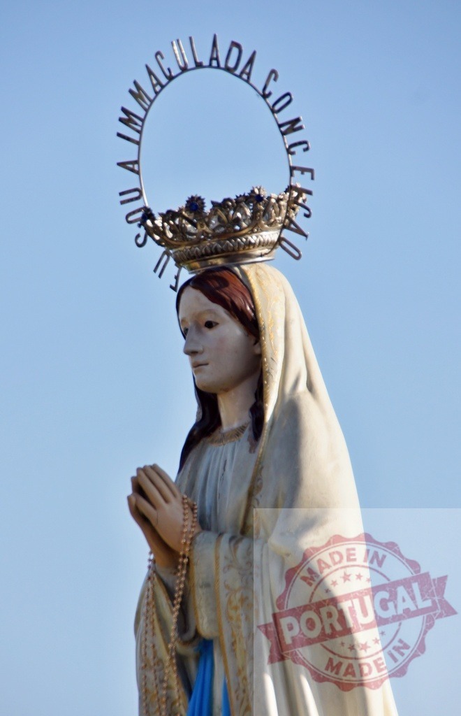Immaculate Conception statue praying with rosary and crown against blue sky | Procession 15.08.2025 - Assumption Day - Paco de Sousa, Portugal Statue of Virgin Mary with crown and halo praying with rosary against blue sky - Realized with Pictrs.com
