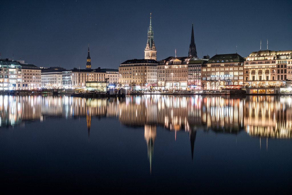 Hamburger Binnenalster bei Nacht mit Spiegelungen | Nächtlicher Blick über die Binnenalster auf die beleuchtete Hamburger Innenstadt mit Rathaus, Kirchtürmen und langen Lichtspiegelungen im ruhigen Wasser. - Realisiert mit Pictrs.com