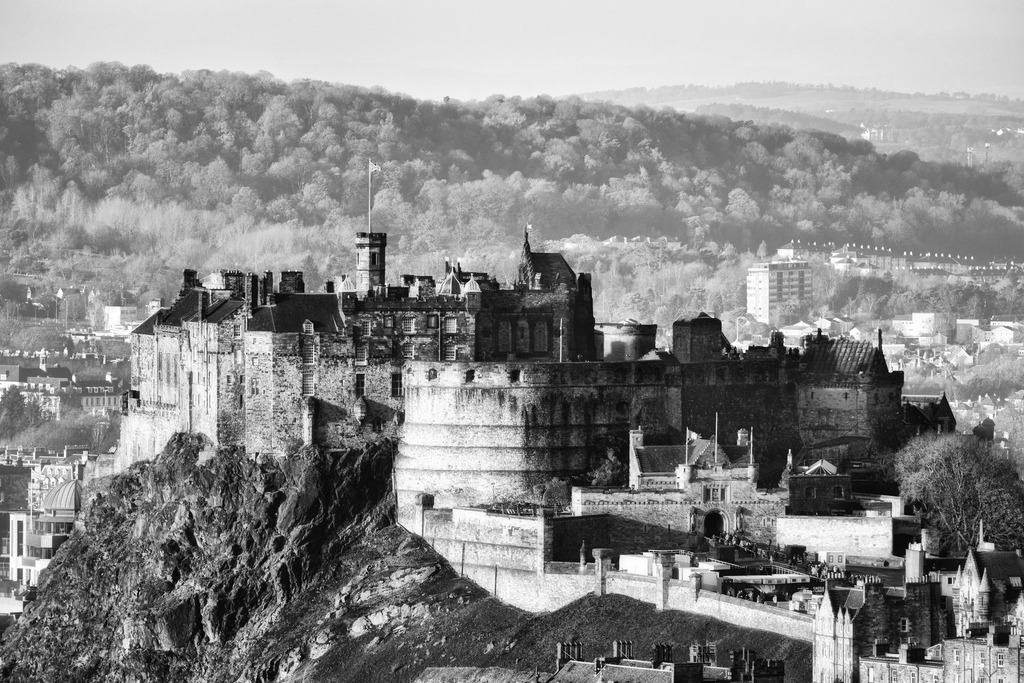 Edinburgh Castle im Winter | Das majestätische Edinburgh Castle thront auf einem felsigen Vulkankegel, umgeben von der historischen Stadtkulisse. Die Schwarz-Weiss-Darstellung betont die architektonischen Details und die dramatische Struktur der Festung. Ein klarer Wintermorgen beleuchtet die alten Mauern und hebt die Kontraste der Szene hervor. - Realisiert mit Pictrs.com