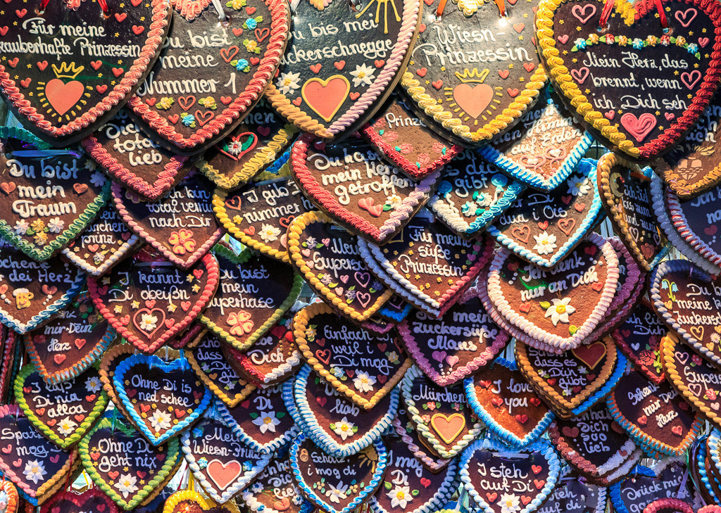 Süße Worte – Lebkuchenherzen vom Oktoberfest | Ein Meer aus Lebkuchenherzen auf der Wiesn – bunt, verspielt und voller liebevoller Botschaften. Zwischen Zuckerguss und Kitsch fängt dieses Bild die besondere Atmosphäre des Oktoberfests ein: ein Fest der Sinne, bei dem Tradition, Freude und bayerische Herzlichkeit Hand in Hand gehen. Ein süßer Blickfang mit hohem Wiedererkennungswert. - Realisiert mit Pictrs.com