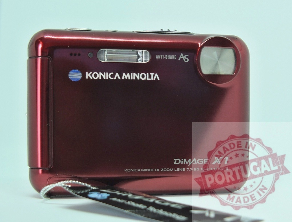 Konica Minolta DiMage X1 red digital camera on white background | Konica Minolta DiMage X1 red digital point and shoot camera, showcasing vintage tech design - Realisiert mit Pictrs.com