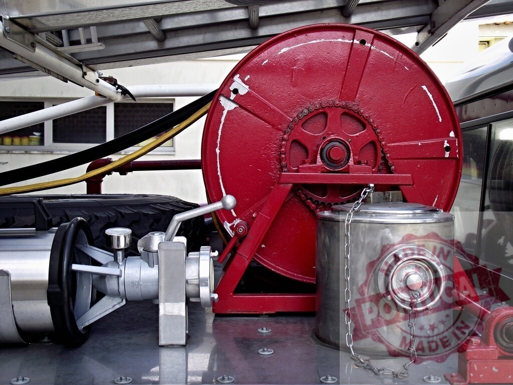 Fire truck equipment with red hose reel | Fire fighting equipment parts on a vehicle deck, including a red hose reel and connections - Realized with Pictrs.com