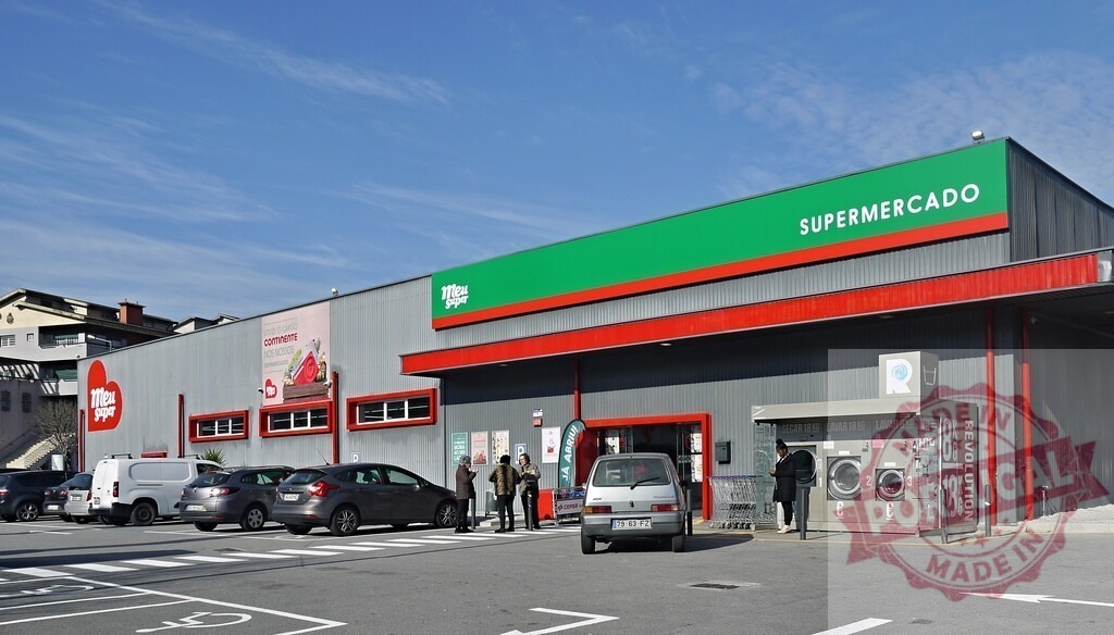 Meu Super supermarket building with parking lot and laundromat | Supermarket exterior with cars in the parking lot and people entering the store and using the self-service laundry - Realized with Pictrs.com