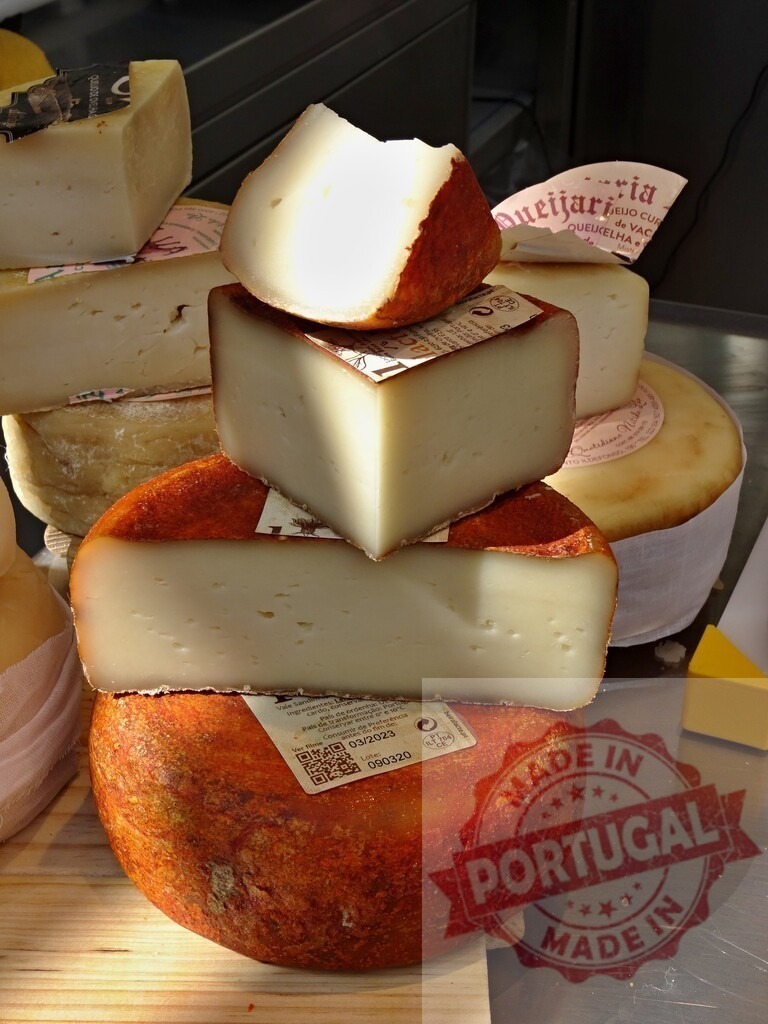 Artisanal cheese wheels and wedges stacking for sale | Tower of artisan cheese wheels and wedges displayed in a market - Realisiert mit Pictrs.com