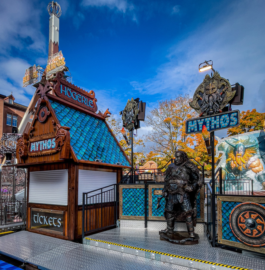 Basel Herbstmesse – Rustikale Mythos Wikinger Attraktion bei Tag | Faszinierende Detail- und Themenfotografie aus Basel: Dieses hochwertige Wandbild fängt die urige Atmosphäre der Wikinger-Attraktion Mythos auf der Basler Herbstmesse ein. Die extrem detailreichen Holzstrukturen, die grimmige Wikinger-Figur und die rustikale Kulisse machen dieses Werk zu einem haptischen Erlebnis. Ein perfekter, charakterstarker Blickfang in Galeriequalität auf Leinwand oder Acrylglas – ideal für Fantasy-Begeisterte und urige Raumkonzepte. - Realisiert mit Pictrs.com