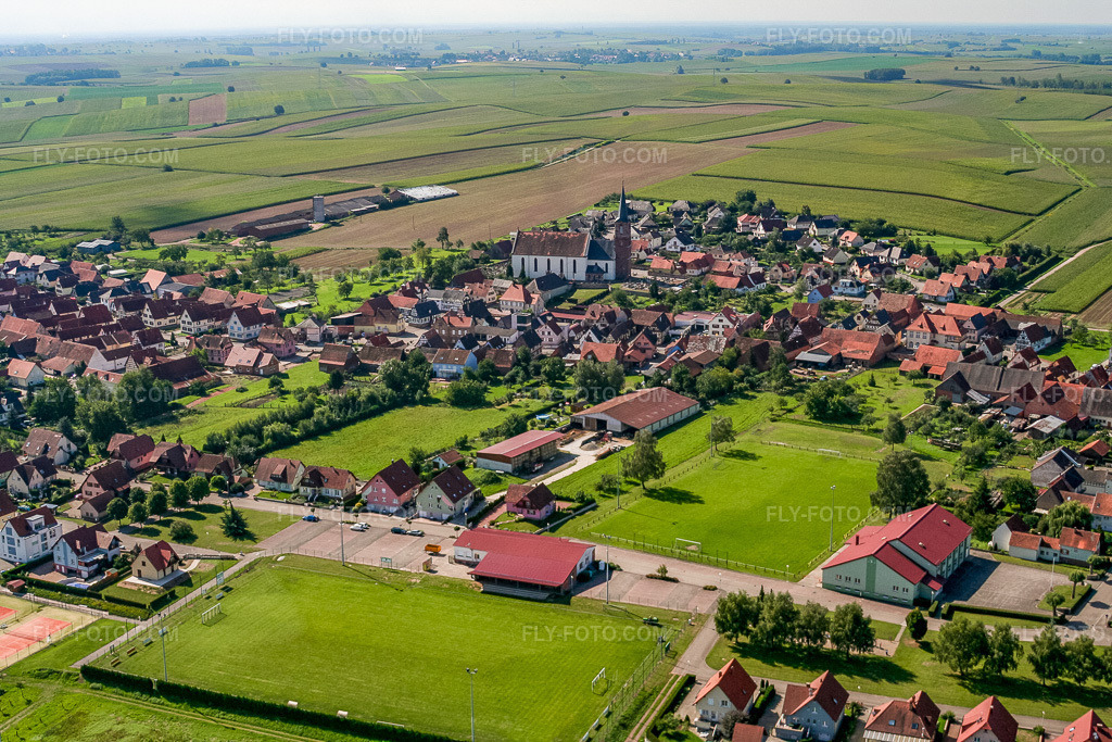 Aerial view: Village center with Stade Municipal - US Schleithal and Église Saint-Barthélemy de Schleithal from the northwest in Schleithal in the state Bas-Rhin, France. – Photo: IMG_3557.jpg taken on 08/31/2006 by Werner Riehm/FLY-FOTO.com – Resolution of the original: 3456 x 2304 px
