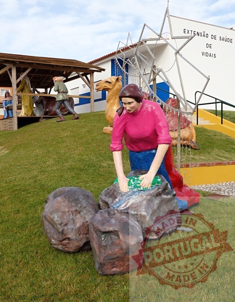 Woman washing clothes in traditional way near nativity scene and Extensão de Saúde de Vidais | Christmas nativity scene with colorful statues of biblical characters and woman washing clothes in traditional way near Extensão de Saúde de Vidais - Realisiert mit Pictrs.com