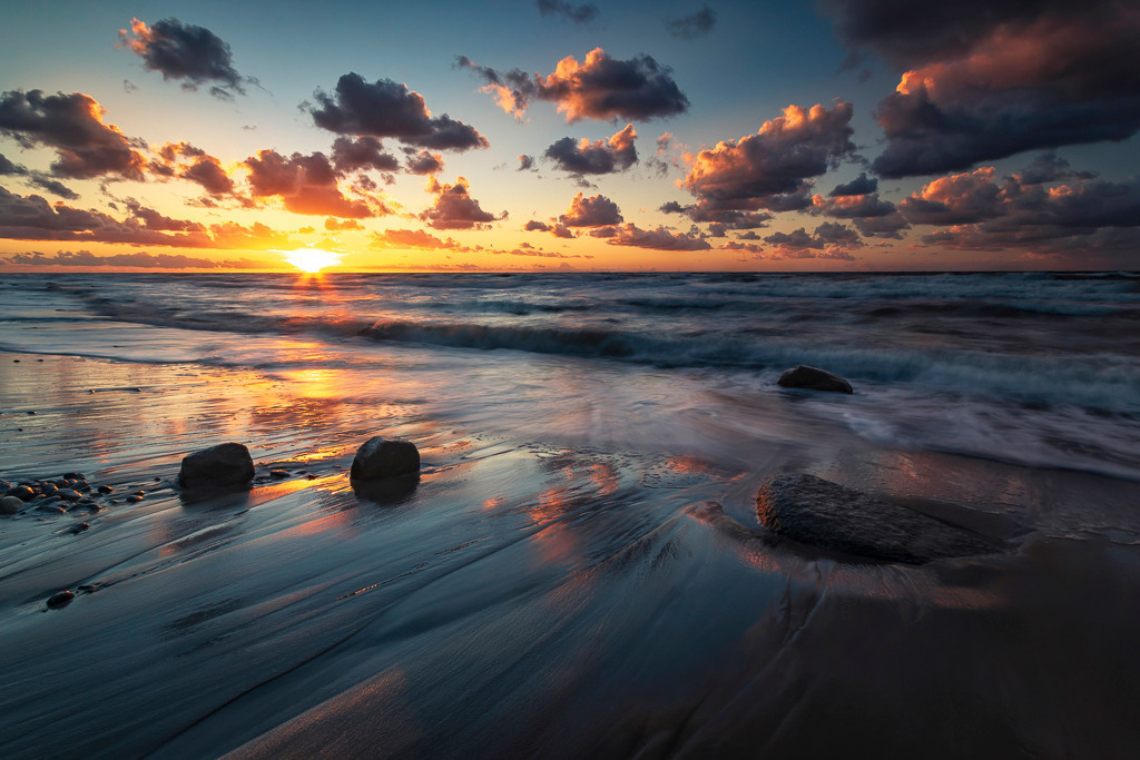 Abendlicht an der Ostsee – Rügen | Sanft rollen die Wellen an den Strand, während die untergehende Sonne Himmel und Wasser in leuchtende Farben taucht. Ein stimmungsvoller Moment an der Küste Rügens, der Ruhe und Weite zugleich ausstrahlt. - Realisiert mit Pictrs.com