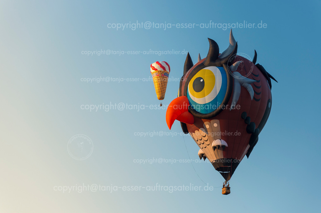 Ein fliegendes Eis und eine Eule am blauen Himmel gibt es auf der WIM zu sehen | Warsteiner Internationale Montgolfiade ist die Veranstaltung mit Heißluftballons. Ballon in Form einer Eule und ein Eis.