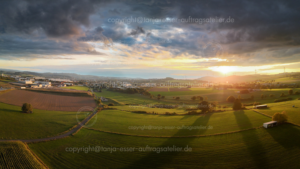 Panorama Luftbild von Brilon aus nördlicher Sicht im Herbst | Luftbild Panorama von Stadt Brilon in Deutschland. Nördliche Ansicht mit landwirtschaftlichen Flächen, Industriegebiet und die Propsteikirche. Wolkiger Herbsttag zur goldenen Stunde.