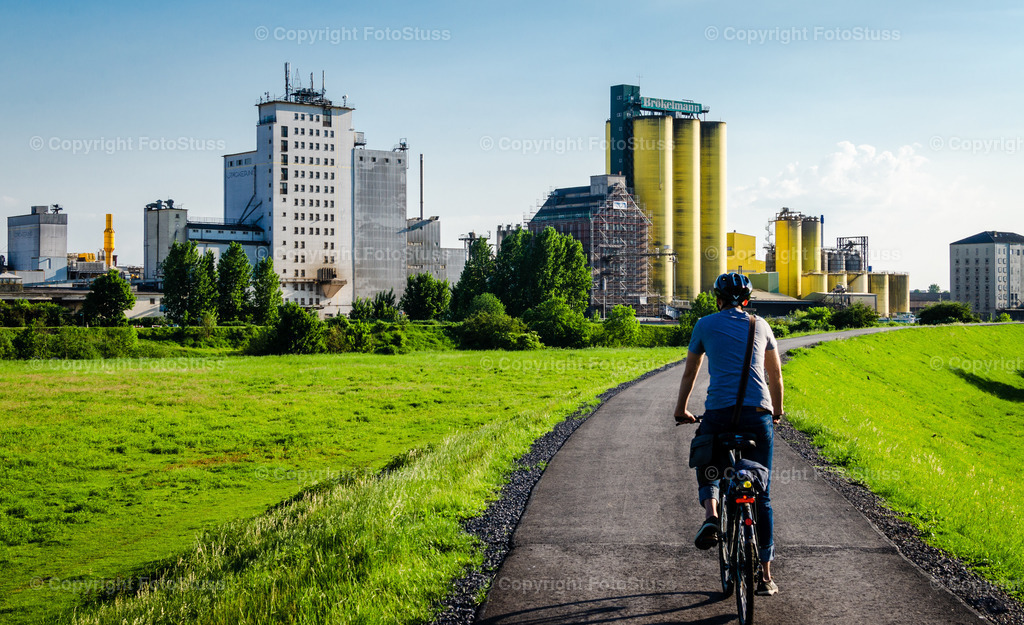 Fahrradfahrer am Hafen Hamm | Ein Fahrradfahrer ist auf einem der vielen Radwege vor der Kulisse des Hammer Hafens unterwegs. - Realisiert mit Pictrs.com