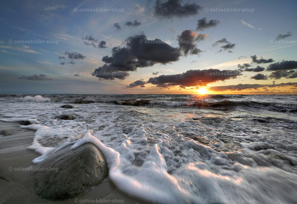 Schaumkronen am Ostseestrand zum Sonnenuntergang | Das Licht der untergehenden Abendsonne beleuchtet die bewegte Ostsee, während eine Welle einen Findling sanft in ein Bad aus Meerschaum hüllt.