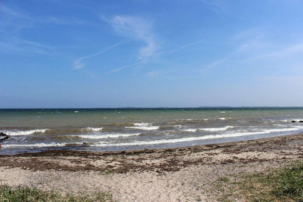 Wandbild: Wellen am Ostseestrand | Dieses Wandbild im Querformat zeigt den Strand in Norgaardholz. Am Himmel sind nur einige Schleierwolken zu sehen.  - Realisiert mit Pictrs.com