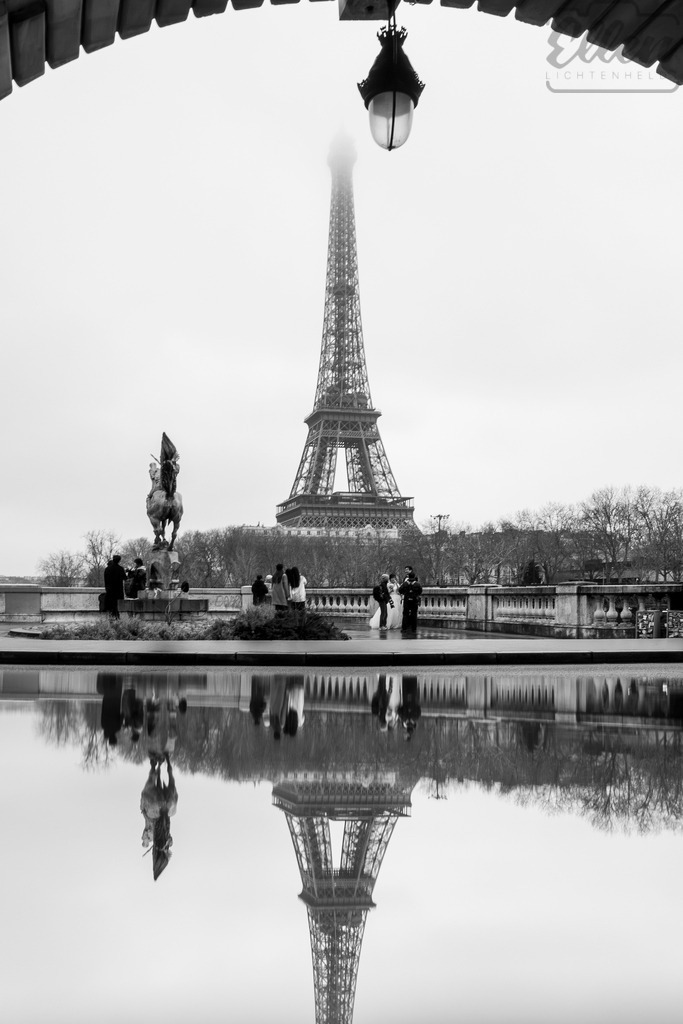 Veil of Light | Through the morning mist, the Eiffel Tower rises like a dream. Reflected in still water, it becomes a delicate balance of light, love, and quiet elegance. - Realisiert mit Pictrs.com