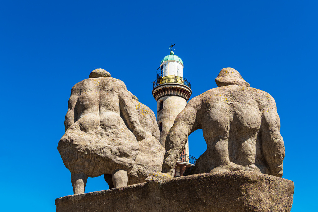 Blick auf den Leuchtturm mit Skulpturen in Warnemünde | Blick auf den Leuchtturm mit Skulpturen in Warnemünde.