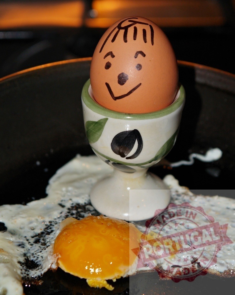 Happy anthropomorphic egg watching another egg frying | Smiling cartoon egg in egg cup observing a fried egg cooking in a pan - Realized with Pictrs.com
