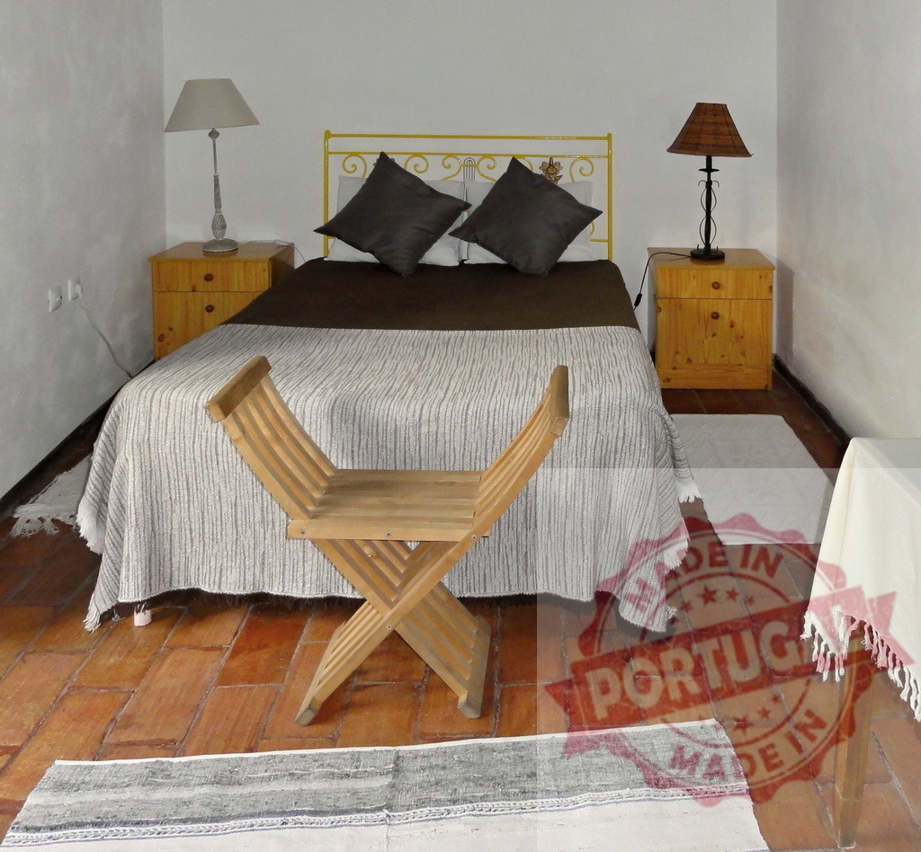 Cozy rustic bedroom interior with wooden furniture | Bedroom interior featuring a double bed, wooden nightstands, lamps, and a folding chair on a tiled floor - Realized with Pictrs.com