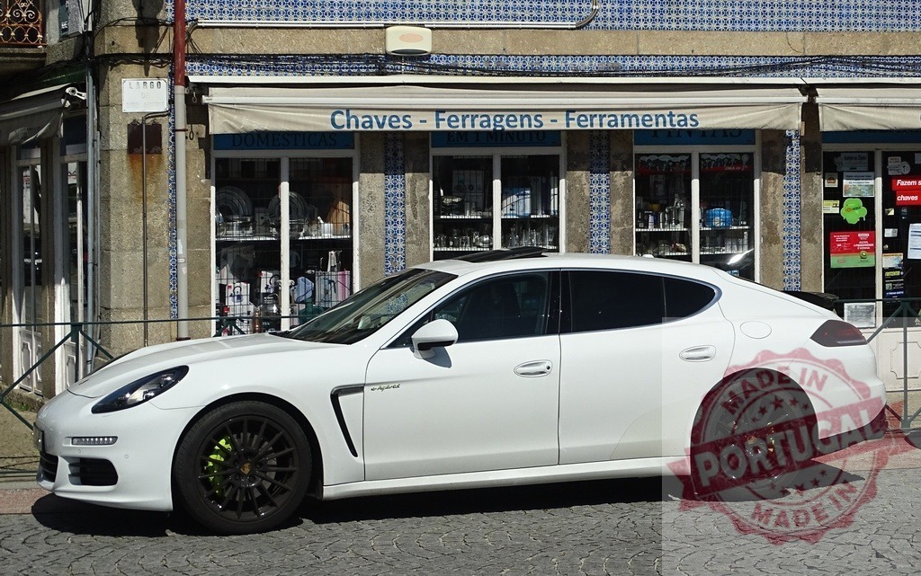 White Porsche Panamera parked at Portuguese hardware store | White Porsche Panamera E-hybrid parked on cobblestone street in front of a traditional Portuguese hardware store - Realized with Pictrs.com