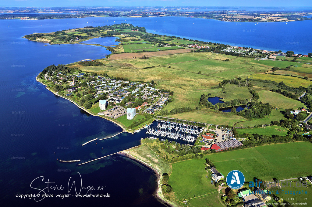 Luftbild Schausende - Der Club Nautic e.V. in Glücksburg-Schausende ist der zentrale Anlaufpunkt für Segler | Der Club Nautic e.V. in Glücksburg-Schausende ist der zentrale Anlaufpunkt für Segler in diesem Küstenort. Der Hafen bietet Liegeplätze für Yachten bis zu 13 Meter Länge bei einer Wassertiefe von bis zu 2,6 Metern. Die Ansteuerung ist tagsüber anhand zweier Hochhäuser und nachts über ein Richtfeuer (121°) einfach und sicher.