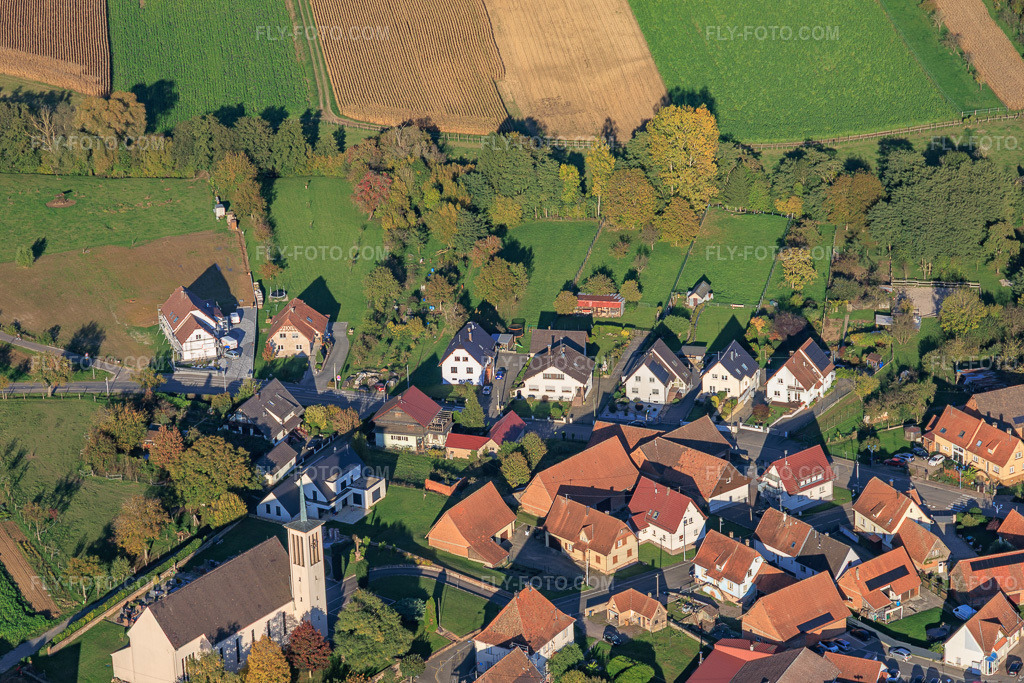Aerial view: Church of St. George and Rue de Wissembourg in Stundwiller in the state Bas-Rhin, France. – Photo: IMG_150149.jpg taken on 10/11/2025 by Werner Riehm/FLY-FOTO.com – Resolution of the original: 5769 x 3846 px