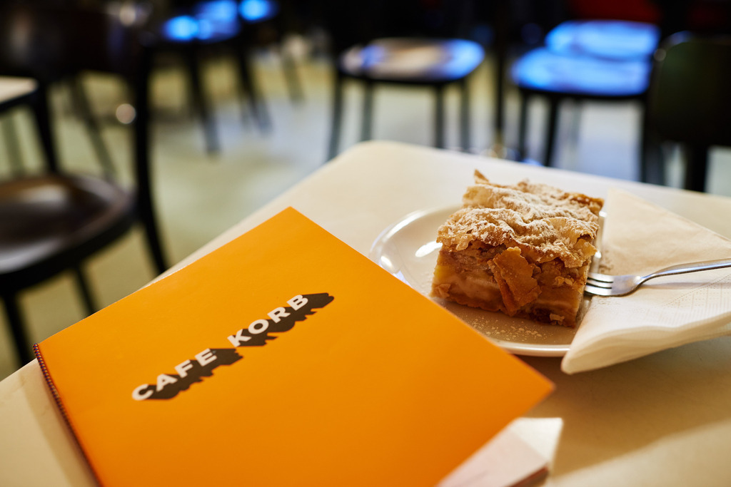 Cafe Korb | Wien, Austria - January 28, 2019: Cafe Korb; ein Apfelstrudel und eine orange Speisekarte stehen auf dem Tisch. - Realisiert mit Pictrs.com