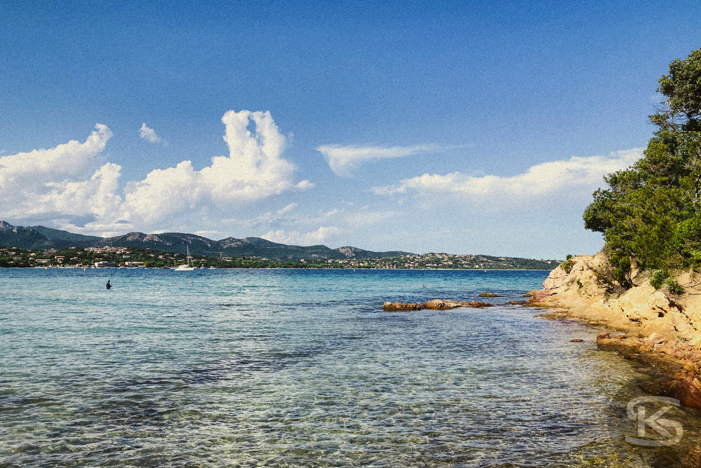 Idyllischer Sandstrand auf Korsika mit kristallklarem Wasser und mediterraner Landschaft | Ein ruhiger, sonnenverwöhnter Sandstrand auf Korsika mit türkisblauem Meer, sanften Wellen und grüner Hügellandschaft im Hintergrund – perfekte Kulisse für einen entspannten Tag in der Natur. - Realisiert mit Pictrs.com