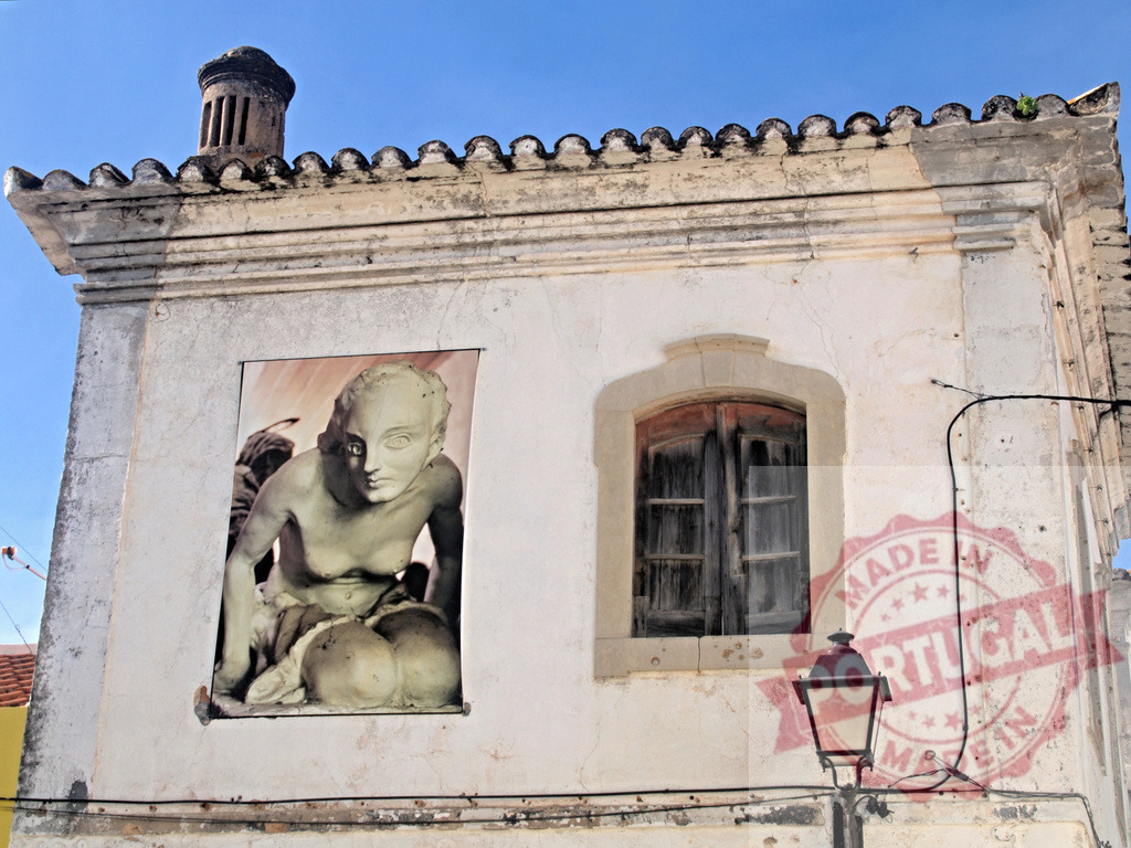 Wall mural of sculpture on old building facade | Sculpture poster on an aged facade with a closed window and street lamp - Realized with Pictrs.com