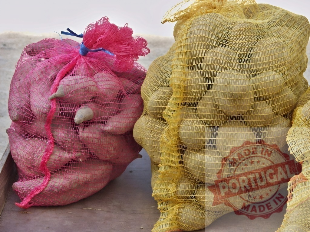 Sweet potatoes and potatoes in mesh bags | Red mesh bag of sweet potatoes next to a yellow mesh bag of potatoes - Realized with Pictrs.com
