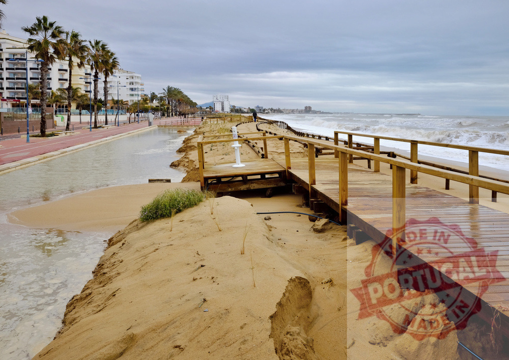 Coastal boardwalk damage after severe beach erosion | Beach boardwalk showing storm damage and severe erosion under a cloudy sky - Realized with Pictrs.com