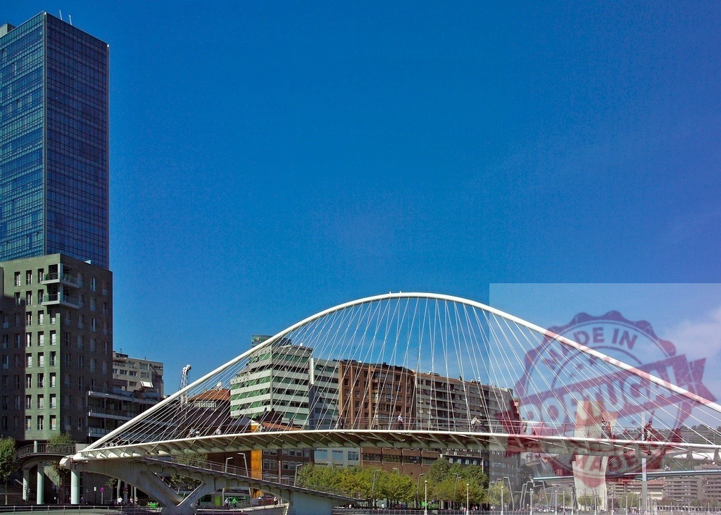 Zubizuri bridge connecting city architecture along Bilbao river. Spain - Bilbao | Zubizuri bridge crossing the Nervion river, with modern architecture and buildings under a clear sky - Realisiert mit Pictrs.com